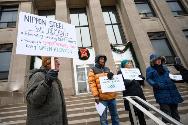 Members of GARD, Gary Advocates for Responsible Development, hold signs on the front steps of the Gary City Hall before a press conference concerning the planned acquisition of U.S. Steel by Japanese company Nippon Steel, on Thursday, Dec. 12, 2024. (Kyle Telechan/for the Post-Tribune)