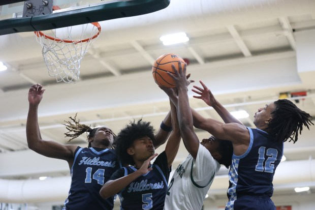 Hillcrest forward Maximilian Carmicle (14), guard Jovian Ratliff (5), Evergreen Park shooting guard Cam Dandridge (12) and guard Gabriel Mobley (12) battle for the rebound during a game at Evergreen Park Community High School in Evergreen Park on Friday, Dec. 6, 2024. (Talia Sprague / Daily Southtown)