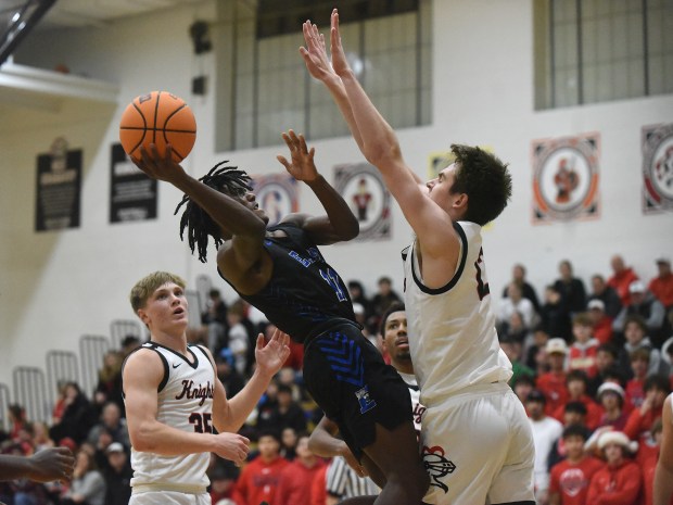 Lincoln-Way East's Jaymon Hornsby (11) tries to shoot over Lincoln-Way Central's Logan Baechtold (12) during a SouthWest Suburban Conference game Tuesday, Dec. 17, 2024 in New Lenox, IL. (Steve Johnston/for the Daily Southtown)