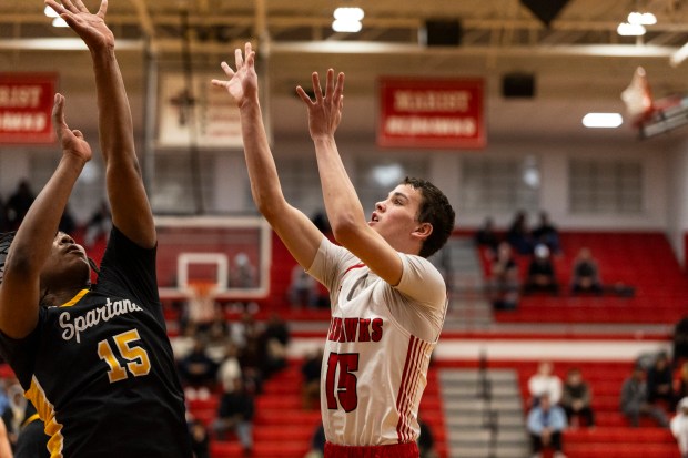 Marist's Ryan Lawlor, right, floats a shot over Marian Catholic's Landon Mays during an East Suburban Catholic Conference game in Chicago on Friday, Dec. 20, 2024. (Vincent D. Johnson / for the Daily Southtown)