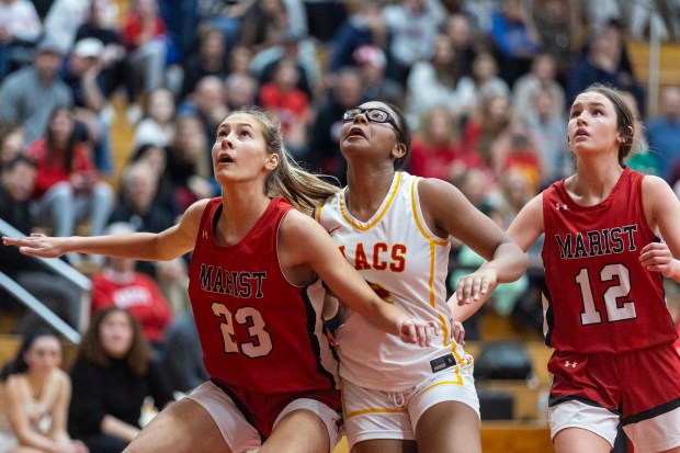 Mother McAuley's Harmony Cooper pushes through Marist's Olivia Barsch (23) and Caroline Flynn (12) for a rebound during a nonconference game in Chicago on Monday, Dec. 9, 2024. (Vincent D. Johnson / for the Daily Southtown)