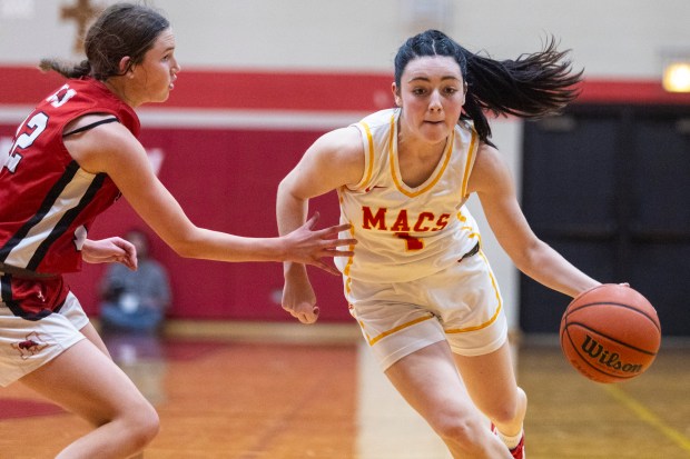 Mother McAuley's Quinn Arundel (1) drives past Marist's Caroline Flynn (12) during a nonconference game in Chicago on Monday, Dec. 9, 2024. (Vincent D. Johnson / for the Daily Southtown)