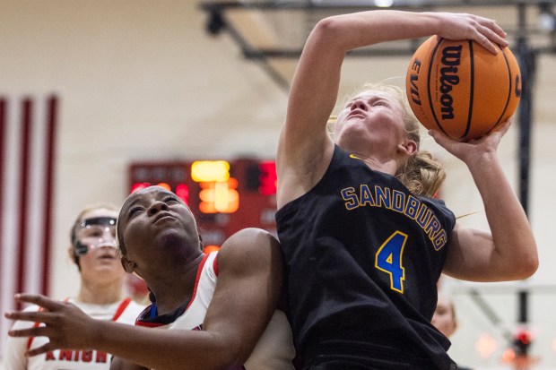 Lincoln-Way Central's Kiya Newson, left, collides with Sandburg's Ellen Driscoll (4) on her shot, sending her to the line for two during a Southwest Suburban Conference game in New Lenox on Thursday, Dec. 5, 2024. (Vincent D. Johnson / for the Daily Southtown)