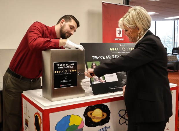 With the help of Archivist Jeremy Pekarek (left), IUN interim Chancellor Vicki Román-Lagunas locks the capsule durning the IUN Time Capsule Sealing Ceremony. The capsule will preserve some of the memories and materials from April 8's solar eclipse. The capsule isn't set to be opened until 2099 when the next eclipse rolls around. The closing ceremony took place on Monday, Dec. 9, 2024. (John Smierciak / Post-Tribune)