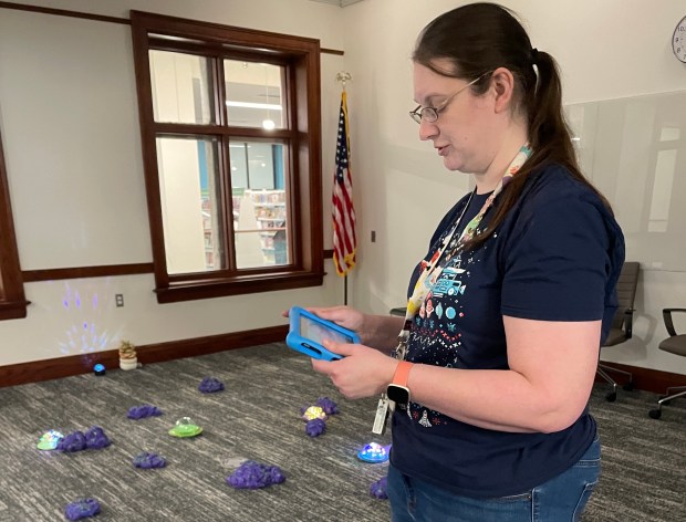 Coral Borg, a youth services associate for the Joliet Public Library, controls a robot amid landscape obstacles similar to how bots used to explore other planets during a Dec. 11 opening for the library's Discover Exoplanets: The Search for Alien Worlds exhibit. (Bill Jones/Daily Southtown)