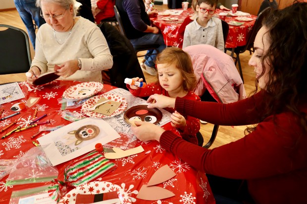 Alicia Rohrlack, from left, Penny Vissering, and Juliana Vissering, create a reindeer craft during the annual "Breakfast with Santa" event December 7, 2024 at Lincolnwood Community Center in Lincolnwood. (Kaitlin Mikrut/for Pioneer Press)