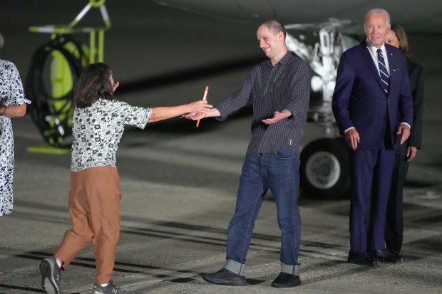 Reporter Evan Gershkovich is greeted on the tarmac by his mother, Ella Milman, as President Joe Biden and Kamala Harris look on at Andrews Air Force Base, Md., following his release as part of a 24-person prisoner swap between Russia and the United States on Aug. 1, 2024. (Manuel Balce Ceneta/AP)