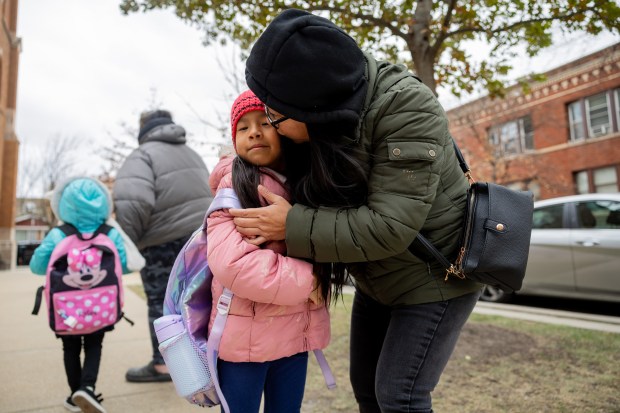 Angelica Juarez picks up her kindergartener Daniela Perez, 5, and fifth-grader Niah Perez, 10, not pictured, from Carlos Fuentes Elementary in the Avondale neighborhood of Chicago on Dec. 11, 2024. In Oct., Acero announced the closures of seven out of 15 schools in its network. (Tess Crowley/Chicago Tribune)