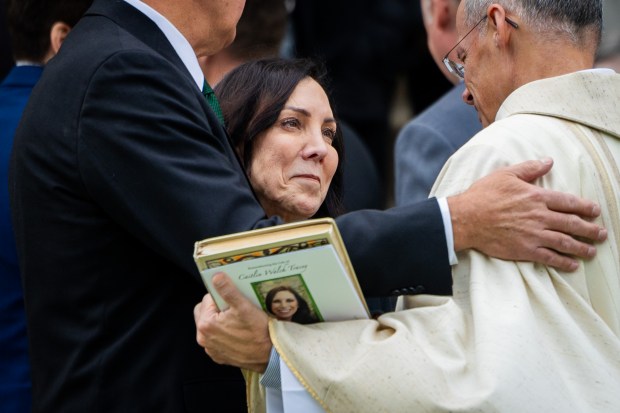 Caitlin Tracey's father, Andrew Tracey, left, and mother, Dr. Monica Tracey, center, embrace the priest after carrying their daughter's casket outside following Caitlin Tracey's funeral at Old St. Patrick's Church on Nov. 23, 2024. Tracey was found dead in a South Loop stairwell ion October. (Tess Crowley/Chicago Tribune)