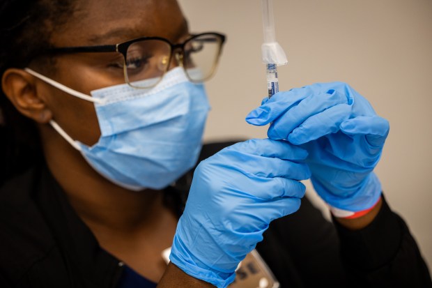 Registered nurse Toko Nzilani prepares a COVID-19 vaccine at a 9th Ward COVID-19 and flu vaccination clinic in the Pullman Community Center in Chicago on Oct. 10, 2024. (Tess Crowley/Chicago Tribune)