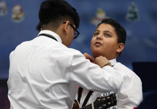 Mariachi student Leo Salgado, 12, right, gets help with his tie from Mark Garcia, 14, before performing in the 61st annual Winter Arts Showcase. (John J. Kim/Chicago Tribune)