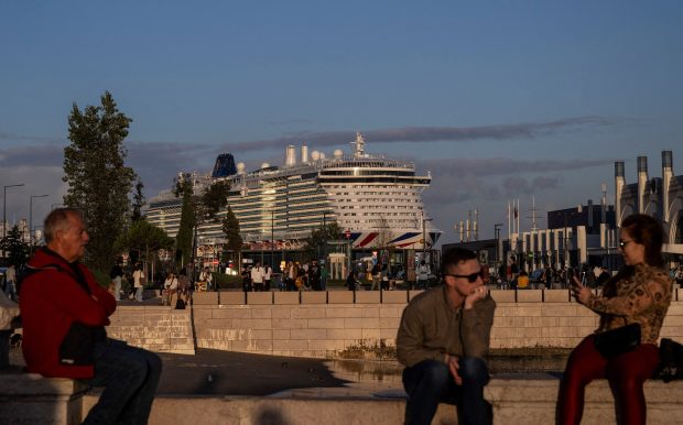 People sit at Cais das Colunas with a docked cruise ship on the Tagus river in Lisbon, Portugal, on Oct. 17, 2024. (Patricia de Melo Moreira/AFP Getty)