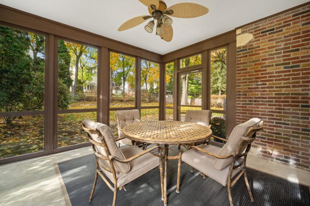 This six-bedroom, 5½-bath home at 312 Sterling Road, Kenilworth, features a living room with 10-foot ceilings, a stone fireplace and a dining area framed by three walls of windows. (Brad Schade)