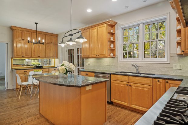 This six-bedroom, 5½-bath home at 312 Sterling Road, Kenilworth, features a living room with 10-foot ceilings, a stone fireplace and a dining area framed by three walls of windows. (Brad Schade)