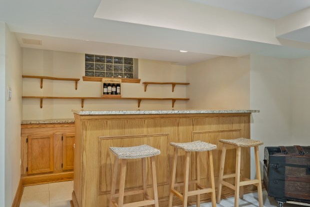 This six-bedroom, 5½-bath home at 312 Sterling Road, Kenilworth, features a living room with 10-foot ceilings, a stone fireplace and a dining area framed by three walls of windows. (Brad Schade)