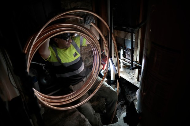 A worker holds coiled copper pipe as it's pulled from the home to a water main in the street in the 3100 block of South Lawndale Avenue on April 10, 2023. The workers replaced the lead service line with copper. (Antonio Perez /Chicago Tribune)