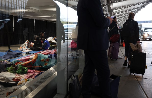 Air passengers and flight crew workers wait for rides as migrant families rest at a temporary shelter inside the bus and shuttle center at O'Hare International Airport on Sept. 27, 2023. (John J. Kim/Chicago Tribune)