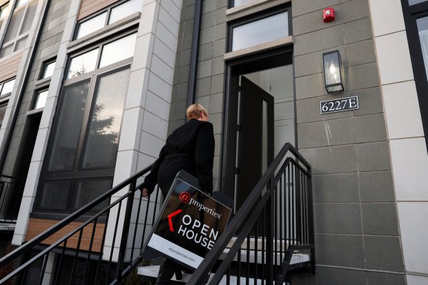 Joanna Olszynska, a Compass real estate broker, brings in a sign after an open house in Woodlawn on Jan. 21, 2024. New York-based Compass is acquiring Chicago-based @properties and Christie's International Real Estate. (Eileen T. Meslar/Chicago Tribune)