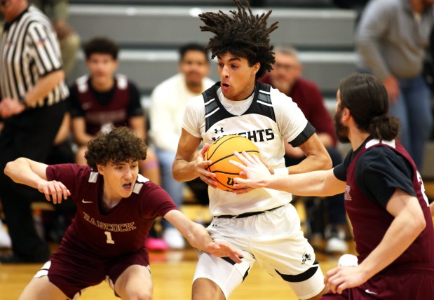 Kaneland's Evan Frieders (11) crashes through Hancock defenders Miguel Chaidez (1) and Joshua Baxter (25) in the second quarter during a non-conference game in Maple Park on Wednesday, Jan. 8, 2025.H. Rick Bamman / For the Beacon News