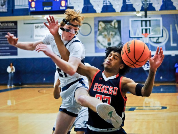 Oswego East's Andrew Pohlman (left) loses the ball as he's fouled by Oswego's Dasean Patton during a game on Saturday, Jan. 11, 2025 in Oswego...(Jon Cunningham/for The Beacon-News)