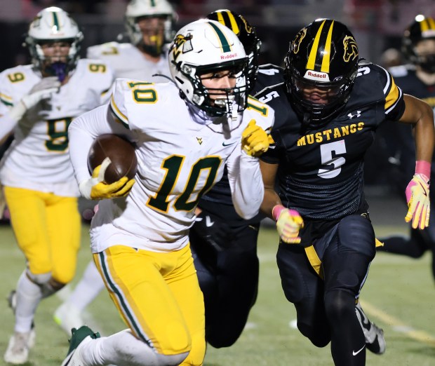 Waubonsie Valley's Josh Tinney, left, runs the ball past Metea Valley players during a game in Aurora on Friday, Oct. 25, 2024. (James C. Svehla / for the Beacon-News)