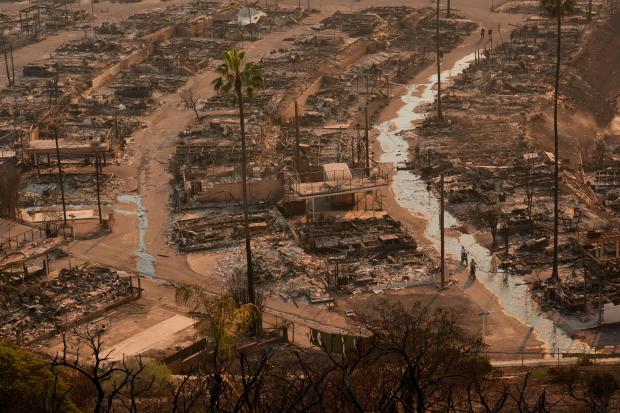 Two people ride bicycles amid the destruction left behind by the Palisades Fire in the Pacific Palisades neighborhood of Los Angeles, Thursday, Jan. 9, 2025. (AP Photo/Jae C. Hong)