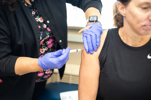 Carrie Thornberry, left, administers a set of vaccine injections for Teresa Huisenga of Highland at the Lake County Health Department's Immunization Clinic, in Crown Point on Thursday, Aug. 31, 2023. (Vincent D. Johnson/for the Post-Tribune).