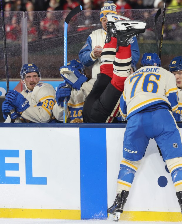 Blackhawks left wing Taylor Hall is checked into the Blues bench by Blues center Zack Bolduc (76) in the first period of the NHL Winter Classic at Wrigley Field on Dec. 31, 2024. (John J. Kim/Chicago Tribune)