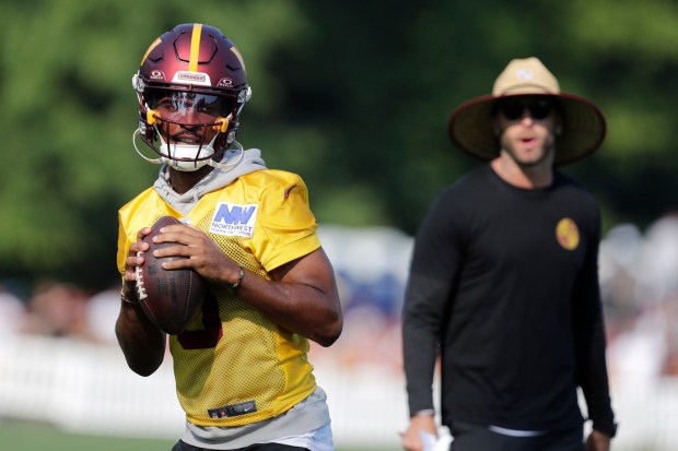 Commanders quarterback Jayden Daniels prepares to pass as offensive coordinator Kliff Kingsbury looks on during a practice at the team's training facility in Ashburn, Va., on Aug. 6, 2024. (AP Photo/Luis M. Alvarez)