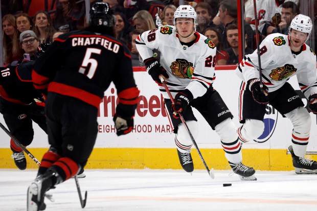 The Blackhawks' Colton Dach controls the puck as he approaches the Hurricanes' Jalen Chatfield during the first period Thursday, Jan. 30, 2025, in Raleigh, N.C. (AP Photo/Karl DeBlaker)