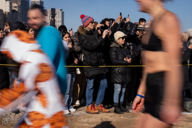 People take photos and record as people make their way out of the frigid waters during Chicago Polar Bear Club's 24th annual Polar Plunge. (Audrey Richardson/Chicago Tribune)