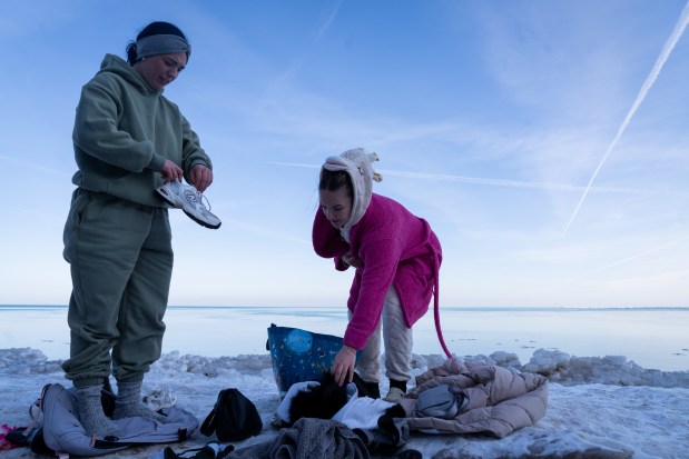 Katelyn Kellogg and Elizabeth Bowles, both from Louisville, Kentucky, pack on layers after participating in Chicago Polar Bear Club's 24th annual Polar Plunge at Oak Street Beach on Jan. 25, 2025. Kellogg is in Chicago for her 25th birthday and wanted to participate as part of their trip. (Audrey Richardson/Chicago Tribune)