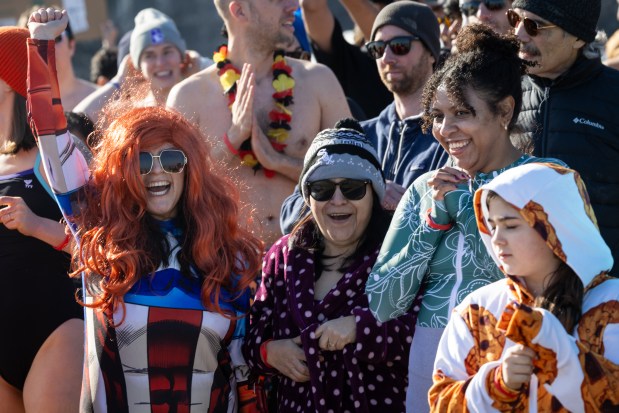 People cheer before entering the water during Chicago Polar Bear Club's 24th annual Polar Plunge at Oak Street Beach. (Audrey Richardson/Chicago Tribune)