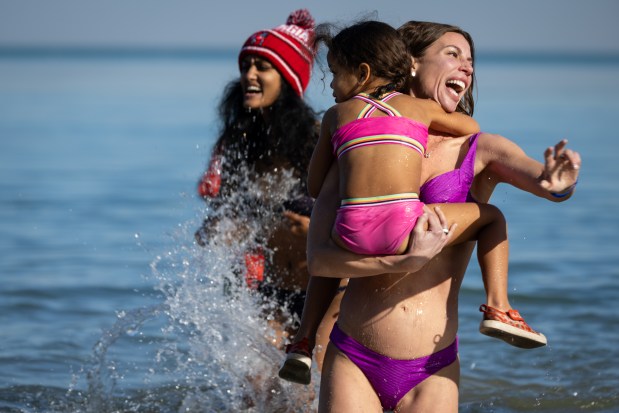 People come out of Lake Michigan after participating in Chicago Polar Bear Club's 24th annual Polar Plunge at Oak Street Beach. (Audrey Richardson/Chicago Tribune)