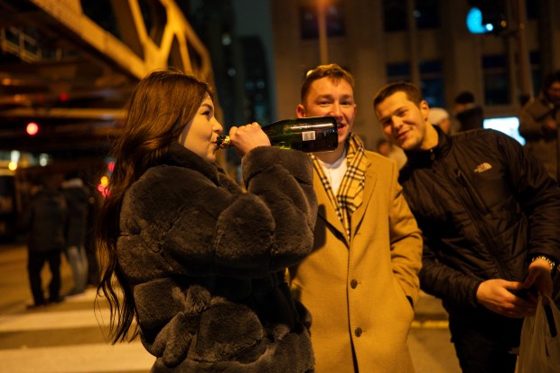 Juliana (last name withheld) shares a bottle of champagne with friends along the Chicago River in the early morning hours of New Year's Day Jan. 1, 2025 in Chicago, Ill. (Vincent Alban/for The Chicago Tribune)