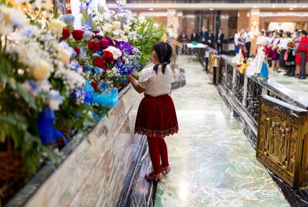 A young girl arranges flowers while parishioners celebrate a Mass in honor of Nuestra Señora Virgen de la Nube, Our Lady of the Cloud, on Jan. 1, 2025, at Our Lady of Mercy on the Northwest Side. The Mass and processional through the Albany Park neighborhood are an annual Ecuadorian community celebration. (Brian Cassella/Chicago Tribune)