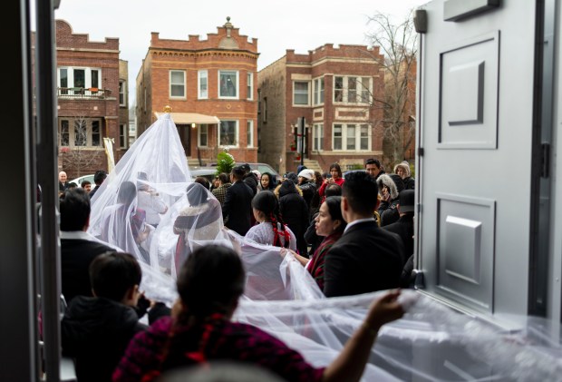 Parishioners carry a train behind a figure out of the church after a Mass in honor of Nuestra Señora Virgen de la Nube, Our Lady of the Cloud, Jan. 1, 2025, at Our Lady of Mercy on the Northwest Side. (Brian Cassella/Chicago Tribune)