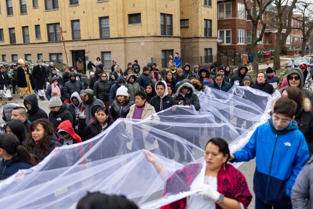 Parishioners carry a train behind a figure in honor of Nuestra Señora Virgen de la Nube, Our Lady of the Cloud, during a processional through the Albany Park neighborhood after Mass on New Year's Day, Jan. 1, 2025, at Our Lady of Mercy on the Northwest Side. The Mass and processional are an annual Ecuadorian community celebration. (Brian Cassella/Chicago Tribune)