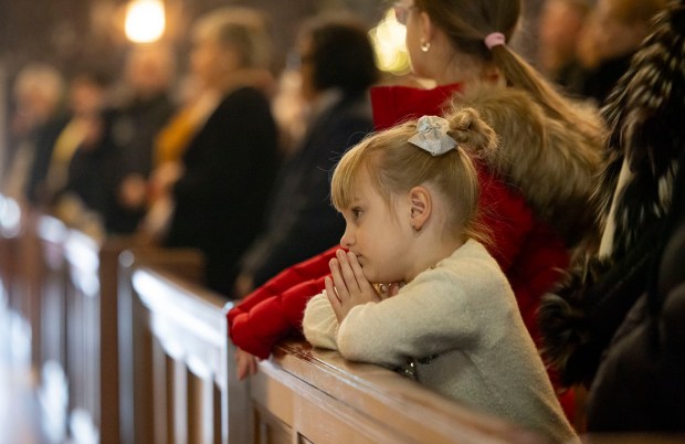 A girl prays while Mass is held on Jan. 5, 2025, at St. Ferdinand Church in Belmont Cragin. The annual event marking the Epiphany mirrors celebrations held in Poland. (Brian Cassella/Chicago Tribune)