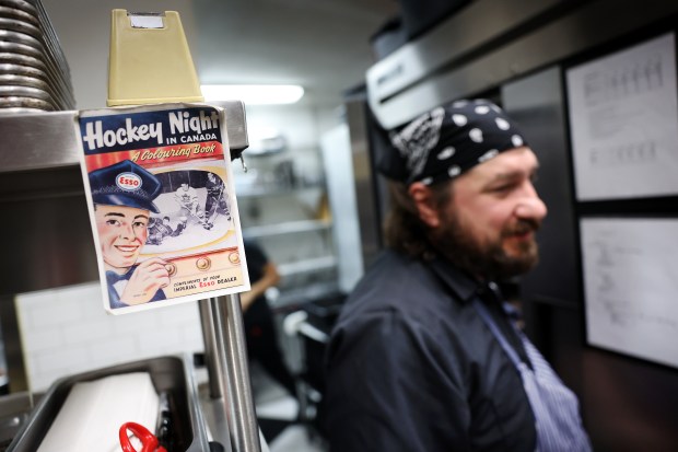 Dear Margaret executive chef Ryan Brosseau walks past a print of a 1950s Hockey Night in Canada coloring book in the kitchen at the Lakeview neighborhood restaurant in Chicago on Jan. 16, 2025. Brosseau grew up in the small town of Merlin, Ontario. (Chris Sweda/Chicago Tribune)