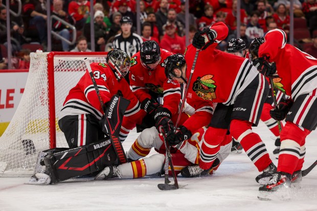 Calgary Flames center Blake Coleman (20) falls on the ice while being surround by Chicago Blackhawks goaltender Petr Mrazek (34), Chicago Blackhawks defenseman Alex Vlasic (72), and Chicago Blackhawks defenseman Louis Crevier (46) during the second period at the United Center Monday Jan. 13, 2025, in Chicago. (Armando L. Sanchez/Chicago Tribune)