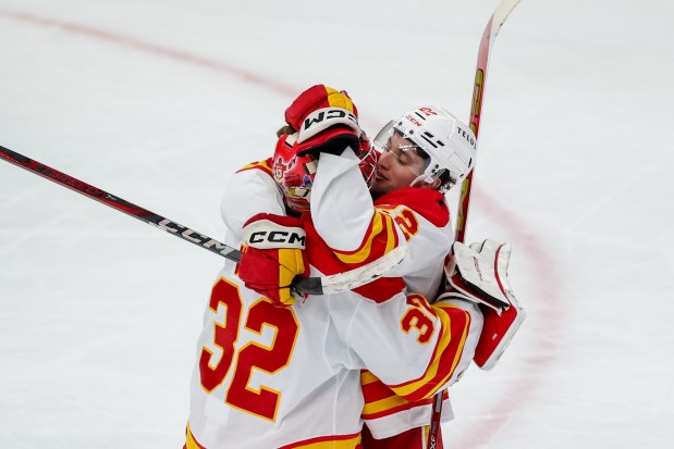 Calgary Flames goaltender Dustin Wolf (32) and Calgary Flames left wing Jakob Pelletier (22) hug after the Flames defeated the Chicago Blackhawks, 5-2, at the United Center Monday Jan. 13, 2025, in Chicago. (Armando L. Sanchez/Chicago Tribune)