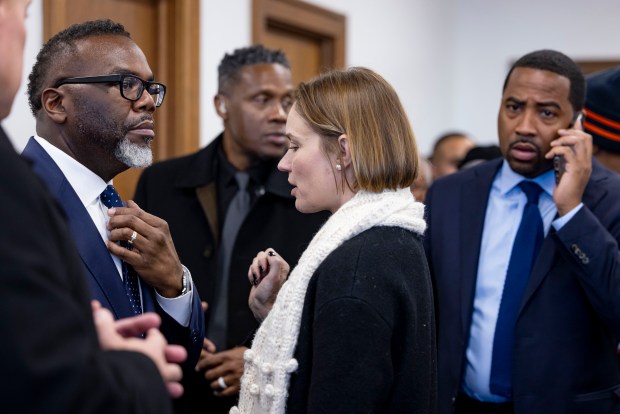 Mayor Brandon Johnson, left, speaks with communications director Erin Connelly before taking questions from reporters, Dec. 5, 2024, at Teamwork Englewood. (Brian Cassella/Chicago Tribune)