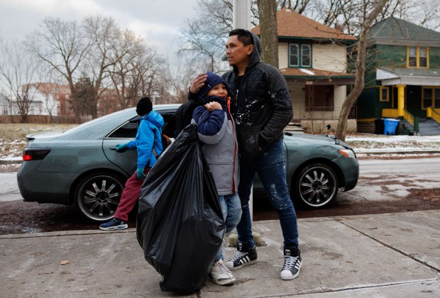 Kelvis Sanchez picks up his son Manuel Farfan, 9, while he carries a bag of toys and clothes given to him at Myra Bradwell School of Excellence in Chicago's South Shore neighborhood on Jan. 8, 2025. (Armando L. Sanchez/Chicago Tribune)