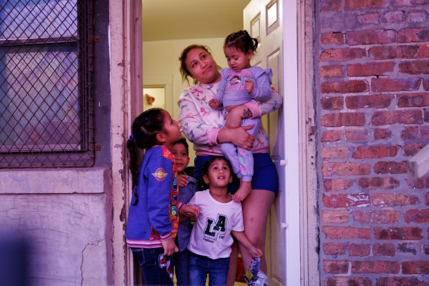 Dariandy Araquez, 6, Alejandro Yovera, 4, and Milago Sofia Sanchez, 4, stand next to to Yorgelis Rangel while she holds her daughter Antonella Sanchez, 2, as the group watches the sunset from the back of Rangel's apartment in Washington Park on Jan. 8, 2025. (Armando L. Sanchez/Chicago Tribune)