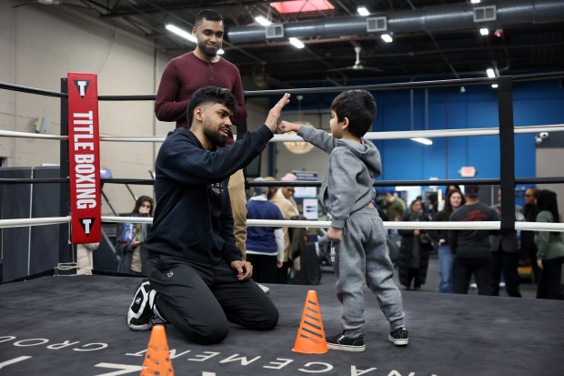 Zain Hussain teaches some boxing skills to Adam Ashrafi, age 3, as Adam's father, Subhaan Ashrafi, looks on during a Muhammad Ali Day event at Body By Khoshal in Northbrook Jan. 17, 2025. (Chris Sweda/Chicago Tribune)