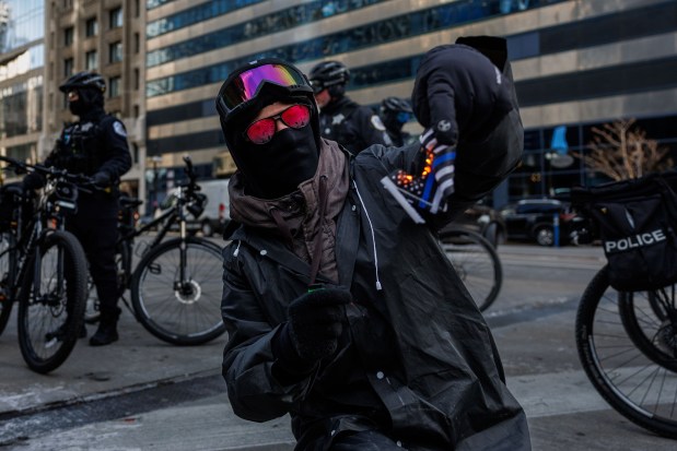 A man burns a small flag while activists protest on East Wacker Drive near Trump International Hotel and Tower on the day of President Donald Trump's inauguration, Jan. 20, 2025, in Chicago. (Armando L. Sanchez/Chicago Tribune)