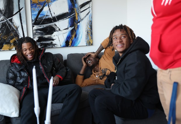 Former Collins Academy High School students Edward Mayes, left, Keontay Fox and Shaun Goss laugh while conversing as they and other former classmates tour a house they helped design on Jan. 9, 2025. (John J. Kim/Chicago Tribune)