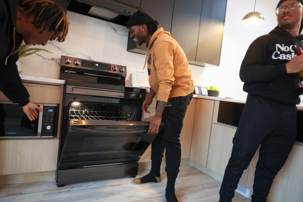 Former Collins Academy High School students Shaun Goss, from left, Keontay Fox and J'Son Kelton playfully show off kitchen appliances during a tour a house they helped design on Jan. 9, 2025. (John J. Kim/Chicago Tribune)