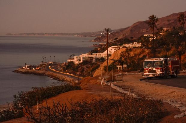 Travis County, Texas Fire Engine 102 is stationed at the Asiliomar Bluffs as the sun rises over homes destroyed by the Palisades Fire in the Pacific Palisades neighborhood of Los Angeles on Jan. 16, 2025. (Damian Dovarganes/AP)